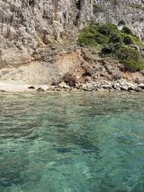 A stunning view of a rocky coastline with crystal-clear waters, perfect for exploring hidden beaches and enjoying nature's beauty.