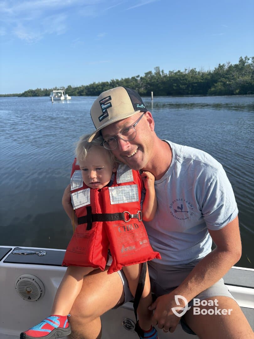 A joyful moment captured on a boat with a father and his child, both wearing life jackets, enjoying a day on the water — perfect for family outings and safe boating experiences.