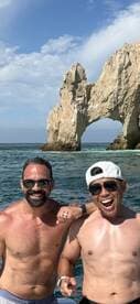 Two friends pose joyfully in front of the iconic Arch of Cabo San Lucas, capturing the essence of a fun day on the water.