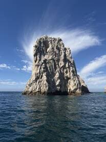 A stunning view of a rocky landmark rising from the ocean under a clear blue sky — perfect for showcasing the natural beauty of coastal destinations.