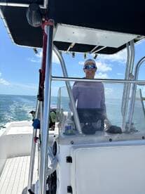 A smiling captain at the helm of a boat, showcasing the interior console and steering area — perfect for navigating the open waters.