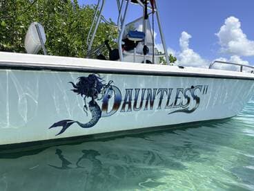 A close-up view of the 'Dauntless II' boat showcasing its unique mermaid design, reflecting beautifully in the clear waters.