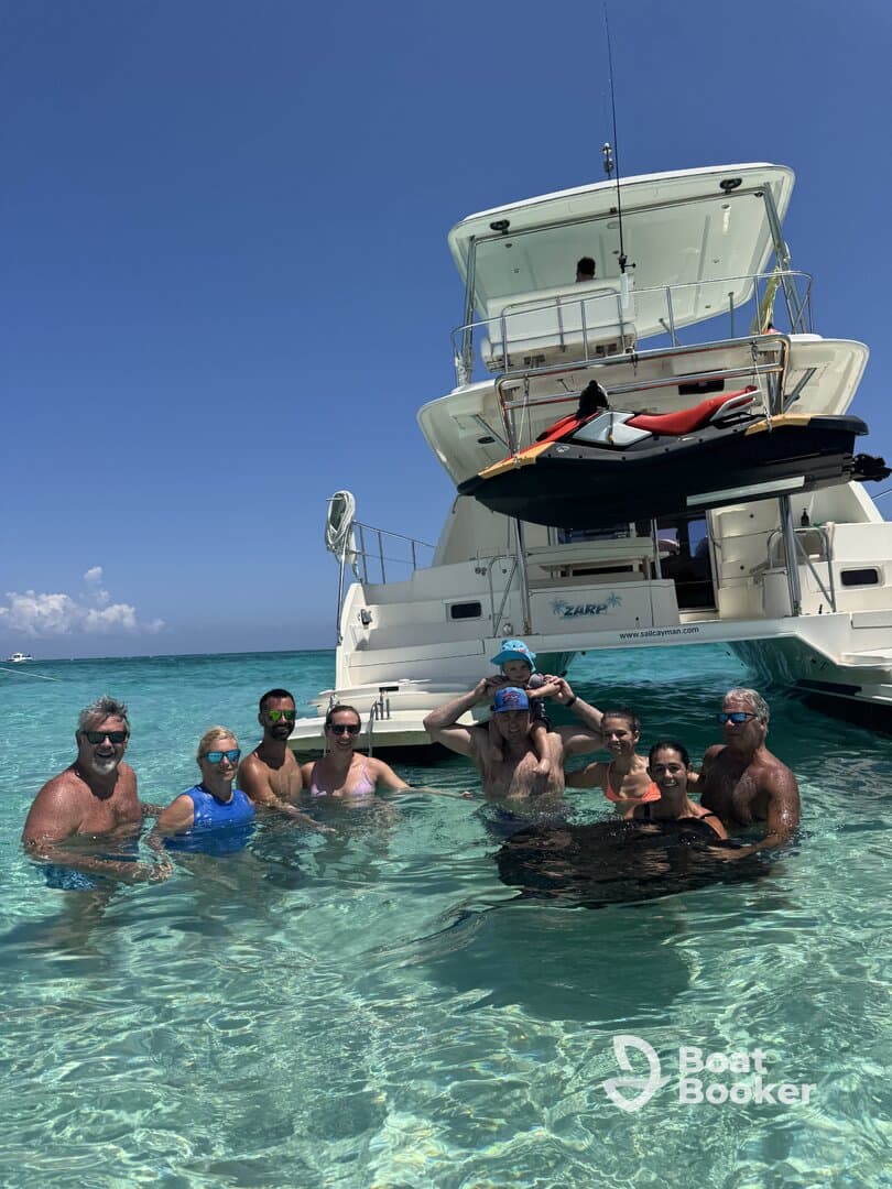A joyful group enjoys a refreshing swim in crystal-clear waters, with a boat anchored nearby, perfect for family outings and fun on the water.