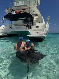 A family enjoys a close encounter with a stingray while swimming in crystal-clear waters, creating unforgettable memories in a tropical paradise.