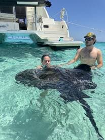 A thrilling encounter as two individuals interact with a stingray in crystal-clear waters, showcasing the unique wildlife experiences available in the Caribbean.