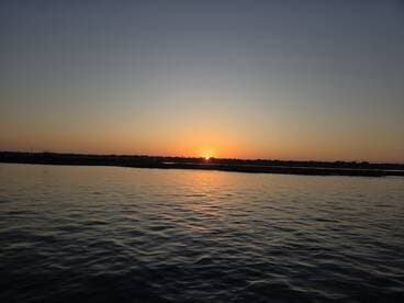 A serene sunset over calm waters, providing a picturesque backdrop for evening boat trips or romantic cruises.