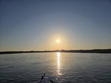 A serene sunset view over calm waters, captured from the bow of a boat, showcasing the tranquil beauty of evening cruises.