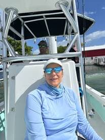 A woman enjoys a sunny day on a boat, showcasing the perfect setting for fishing or leisure activities on the water.