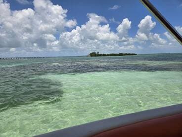 A stunning view of a tropical coastline with vibrant turquoise waters and a distant island, perfect for showcasing the beauty of a boating adventure.