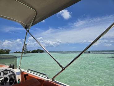 A scenic view from a boat with clear turquoise waters and people snorkeling in the distance, showcasing the beauty of a tropical getaway.