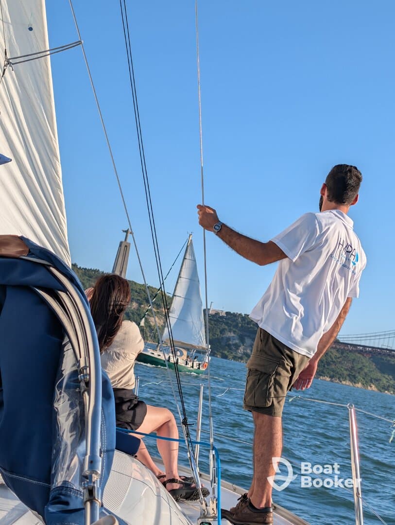A group enjoys a sailing experience on the water, with another sailboat visible in the background, capturing the essence of adventure and camaraderie.