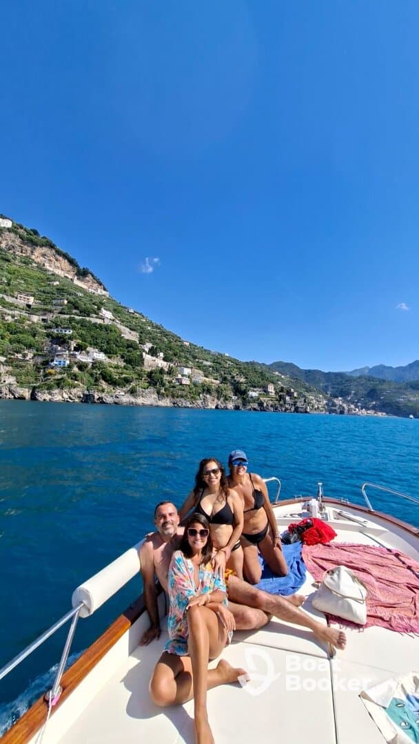 A cheerful group enjoys a sunny day on a boat, soaking in the stunning coastal views — perfect for memorable outings and celebrations on the water.