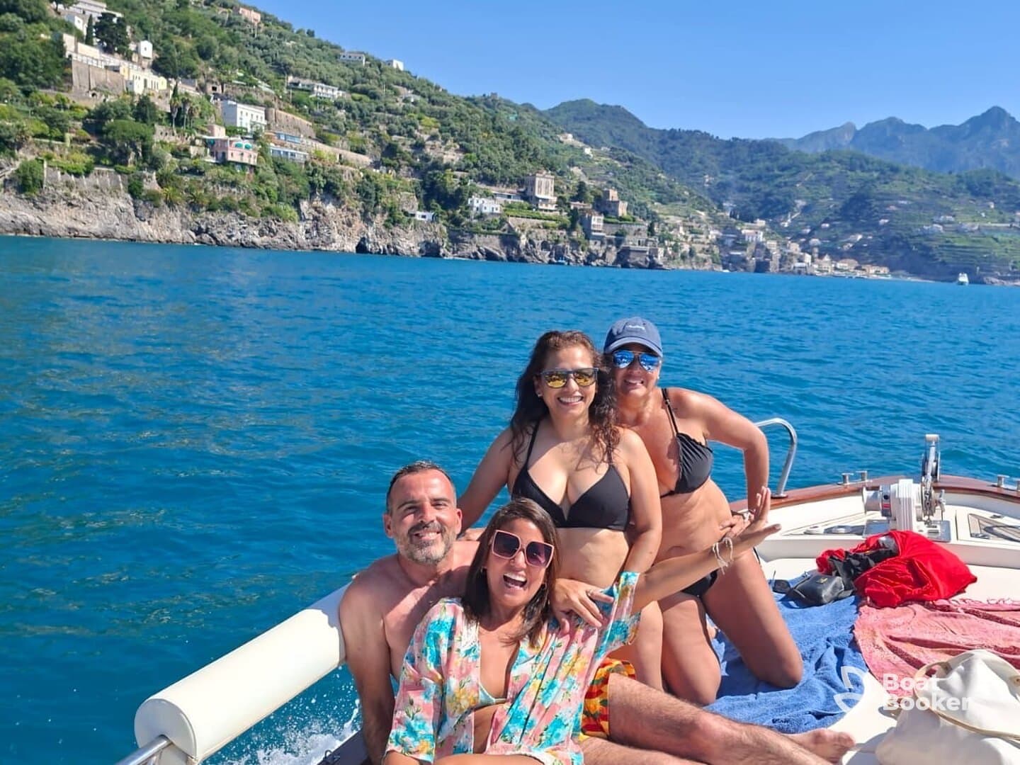 A joyful group of friends enjoys a sunny day on a boat, showcasing the stunning coastline in the background — perfect for memorable outings and celebrations on the water.