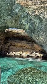 A stunning view of a natural cave along the coastline, with crystal-clear turquoise waters reflecting the sunlight — a perfect destination for exploration and adventure.