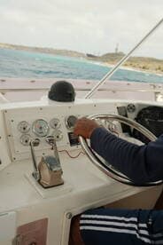 A close-up view of the helm inside a boat, showcasing the steering wheel and control panel, perfect for navigating the open waters.