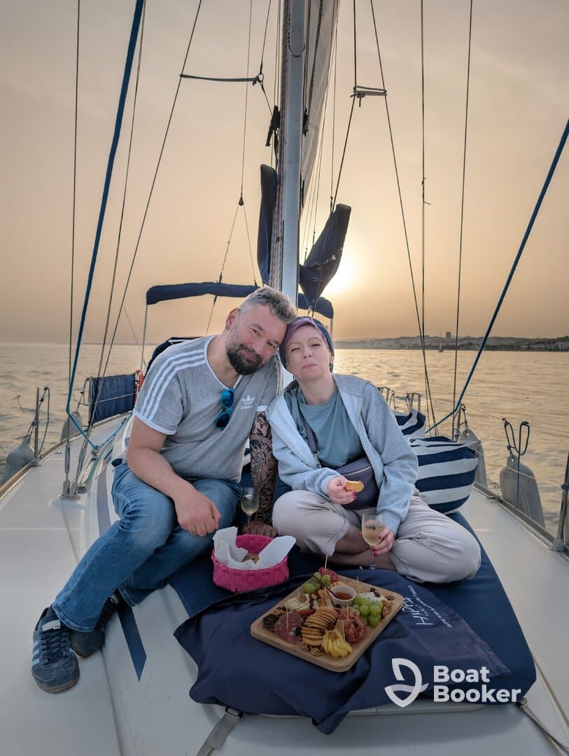 A couple enjoys a romantic sunset on a yacht, sharing a delicious spread of food and drinks — perfect for intimate celebrations on the water.