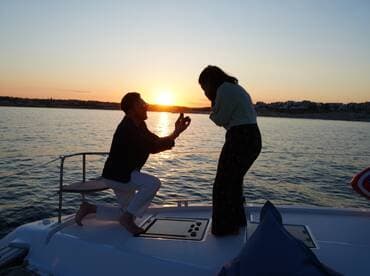 A romantic sunset proposal on a yacht captures a couple in a heartfelt moment, making it a perfect backdrop for unforgettable memories.