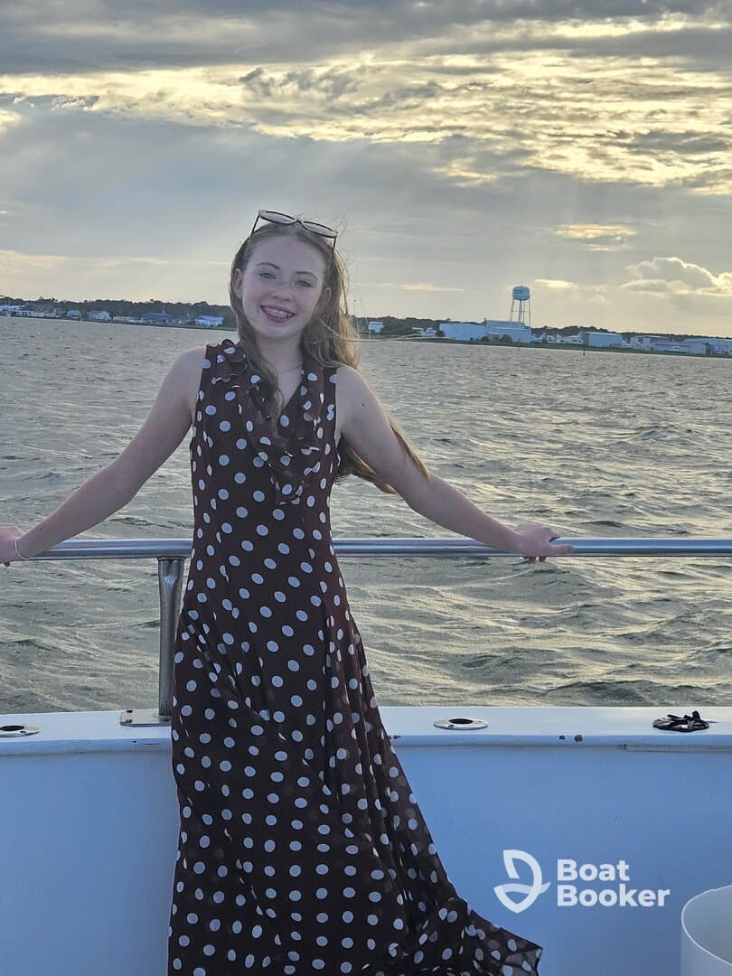 A young girl smiles while enjoying a boat ride, with the ocean and a beautiful sky in the background — a perfect moment for family adventures on the water.