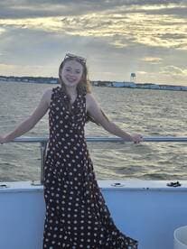 A young girl smiles while enjoying a boat ride, with the ocean and a beautiful sky in the background — a perfect moment for family adventures on the water.