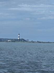 A picturesque view of a lighthouse standing tall against a serene backdrop of water and sky, perfect for capturing the essence of coastal adventures.