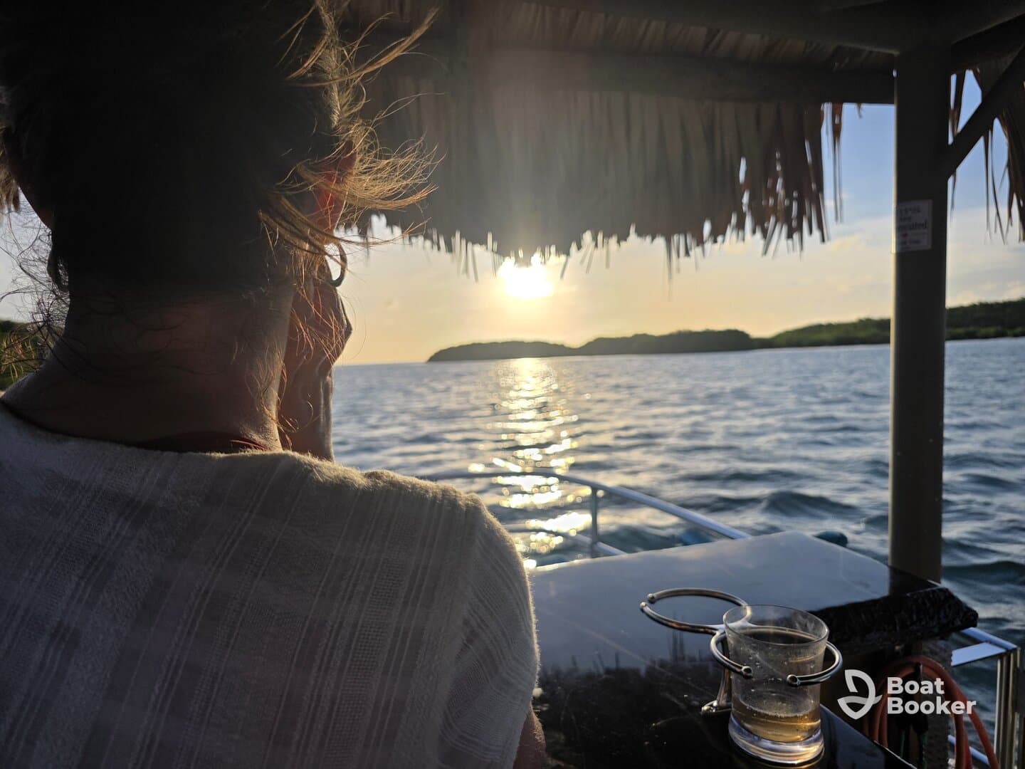A serene sunset view from a boat, featuring a guest enjoying the moment with a drink in hand — perfect for capturing the essence of relaxation on the water.