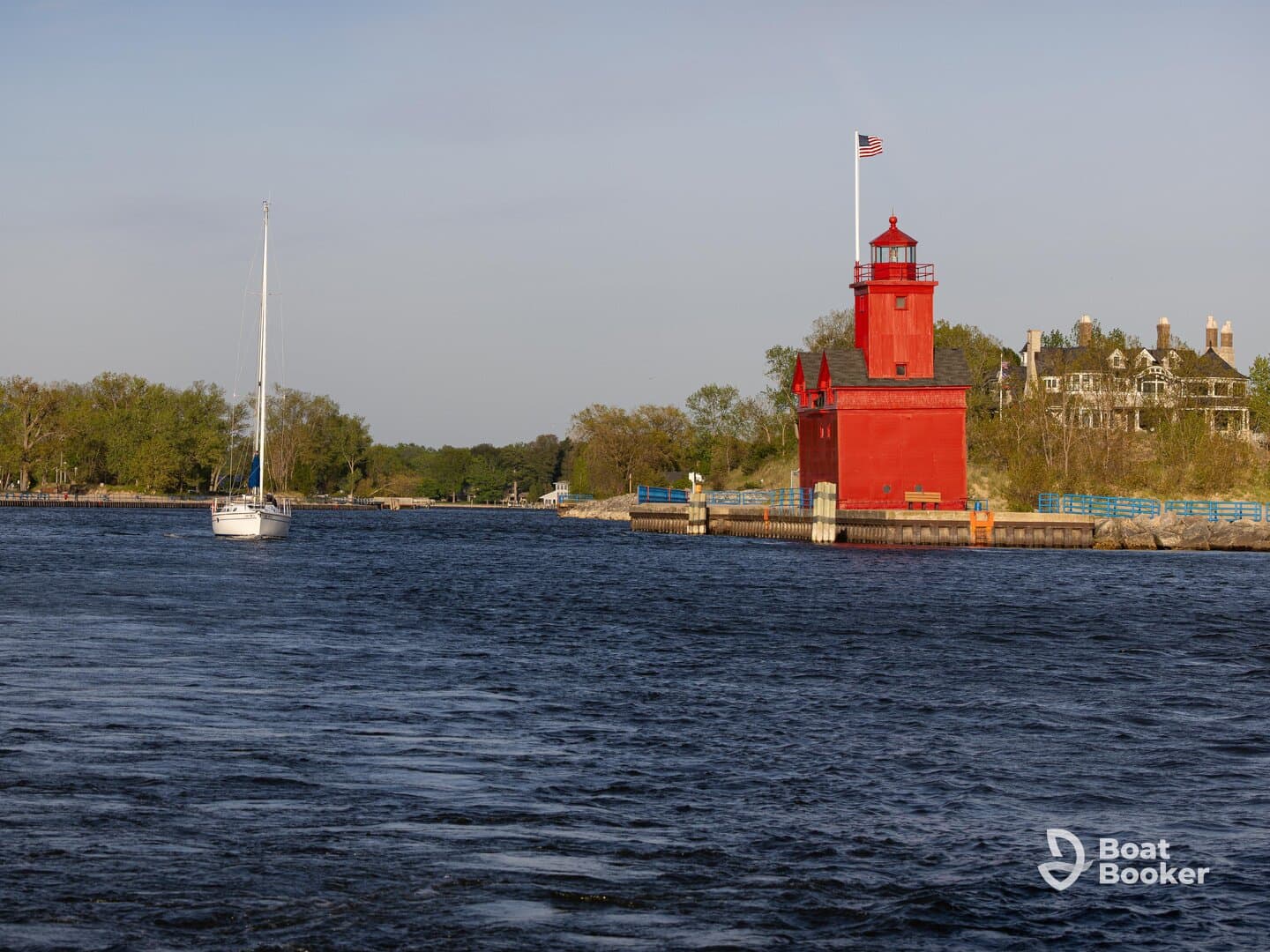 A serene view of a sailboat navigating past a vibrant red lighthouse, showcasing the beauty of coastal scenery and maritime architecture.