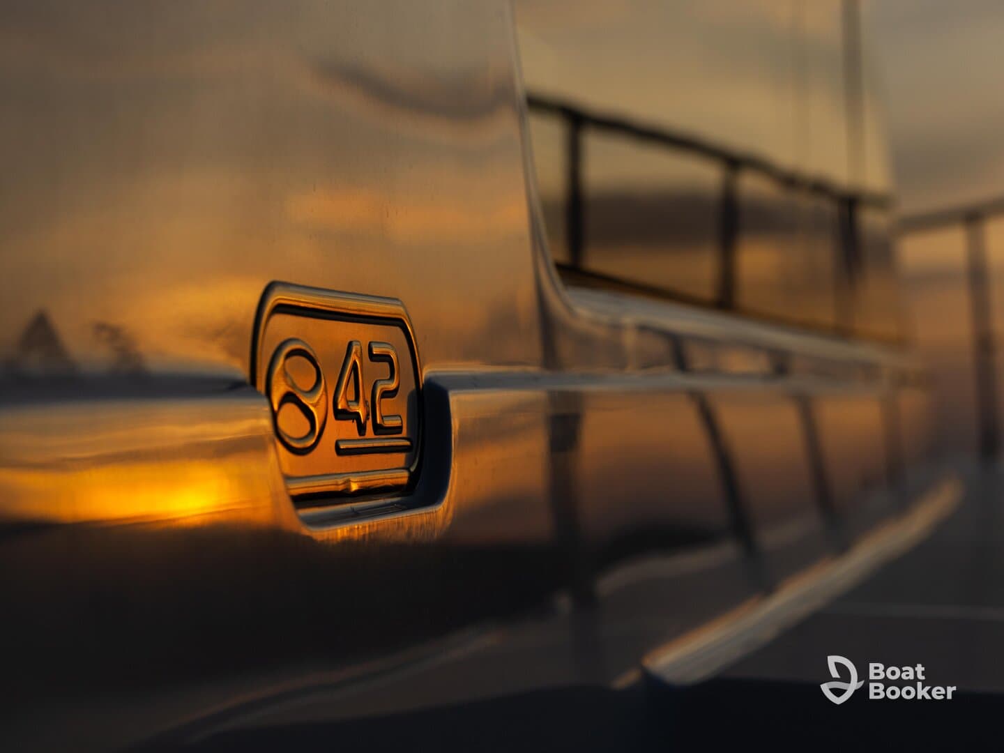 Close-up shot of the side of a boat featuring the number '842' reflecting the warm hues of sunset, showcasing the vessel's sleek design.