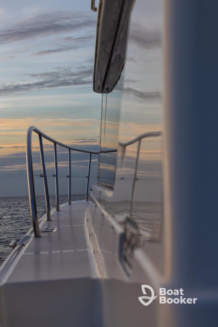 A sleek view of a boat's side railing reflecting the serene colors of the sky at sunset, showcasing the beauty of being underway on the open water.