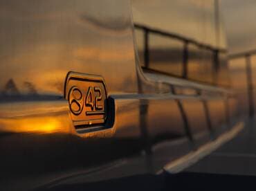 Close-up shot of the side of a boat featuring the number '842' reflecting the warm hues of sunset, showcasing the vessel's sleek design.