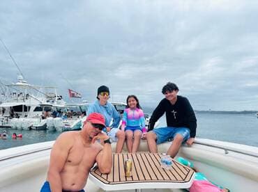 A cheerful group of friends and family enjoy their time on a boat, showcasing a fun day on the water with swimming and relaxation.