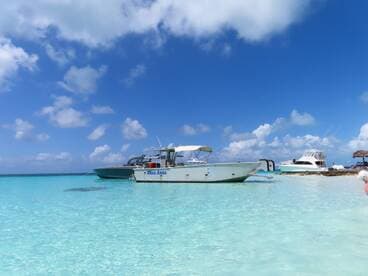 A scenic view of the 'Miss Anna' boat anchored in crystal-clear waters, perfect for enjoying the sun and sea.