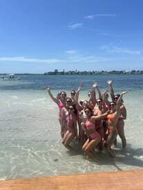 A lively group of friends celebrates at the beach, enjoying the sun and water — perfect for a fun day out with friends.