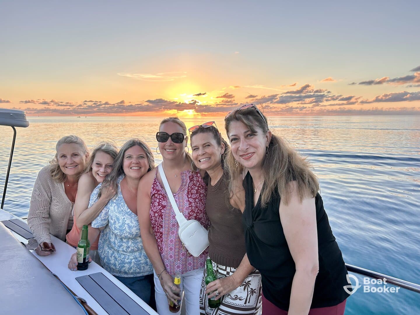 A joyful group of friends poses together on a yacht at sunset, capturing a perfect moment of celebration and camaraderie on the water.