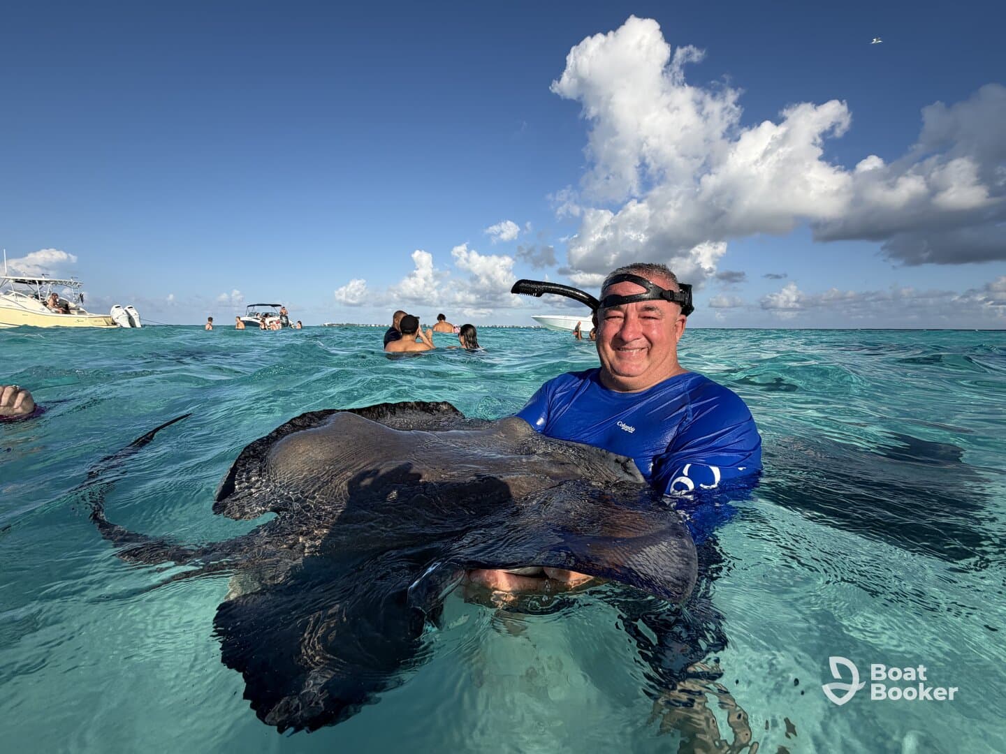 A man joyfully interacts with a stingray in the clear waters, showcasing a memorable wildlife experience in a tropical setting.