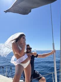 A joyful bachelorette celebration aboard a yacht, featuring the bride-to-be in a stylish outfit and a friend raising a glass of champagne — perfect for unforgettable moments on the water.