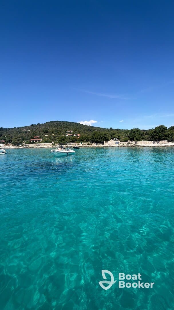 A picturesque view of turquoise waters with boats anchored along the coastline, showcasing the stunning natural beauty of the area.