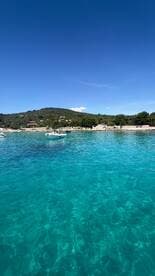 A picturesque view of turquoise waters with boats anchored along the coastline, showcasing the stunning natural beauty of the area.