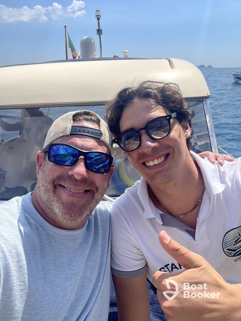 Two friends take a cheerful selfie aboard a boat, capturing a moment of fun and camaraderie on the water.
