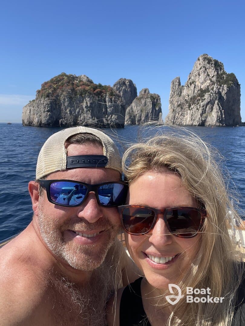 A couple enjoys a sunny day on the water, capturing a selfie with stunning rock formations in the background — perfect for romantic getaways or adventure trips.