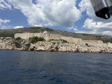 A stunning view of a historic fortress perched on rocky cliffs, surrounded by the beautiful coastline — a perfect destination for sightseeing and exploration by boat.