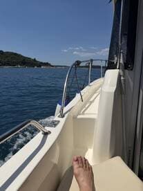 A close-up view of a foot resting on the seating of a boat, showcasing a relaxing moment on the water with a scenic backdrop.