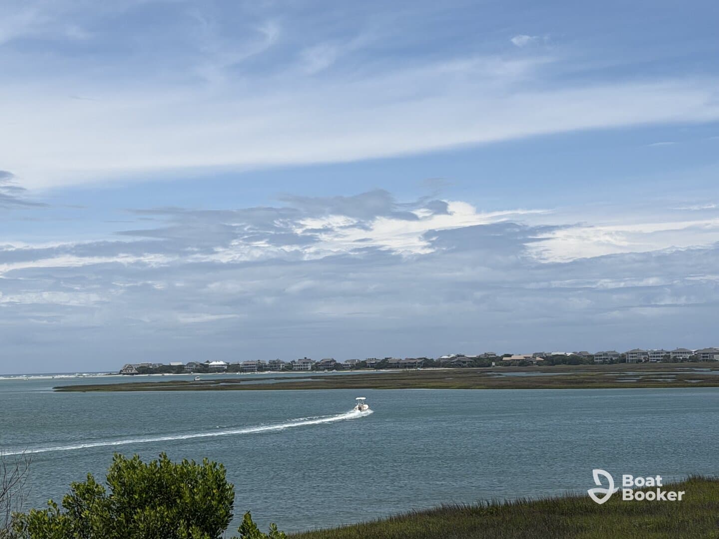 A scenic view of a boat navigating through tranquil waters, surrounded by lush greenery and coastal homes, perfect for showcasing the beauty of a day on the water.