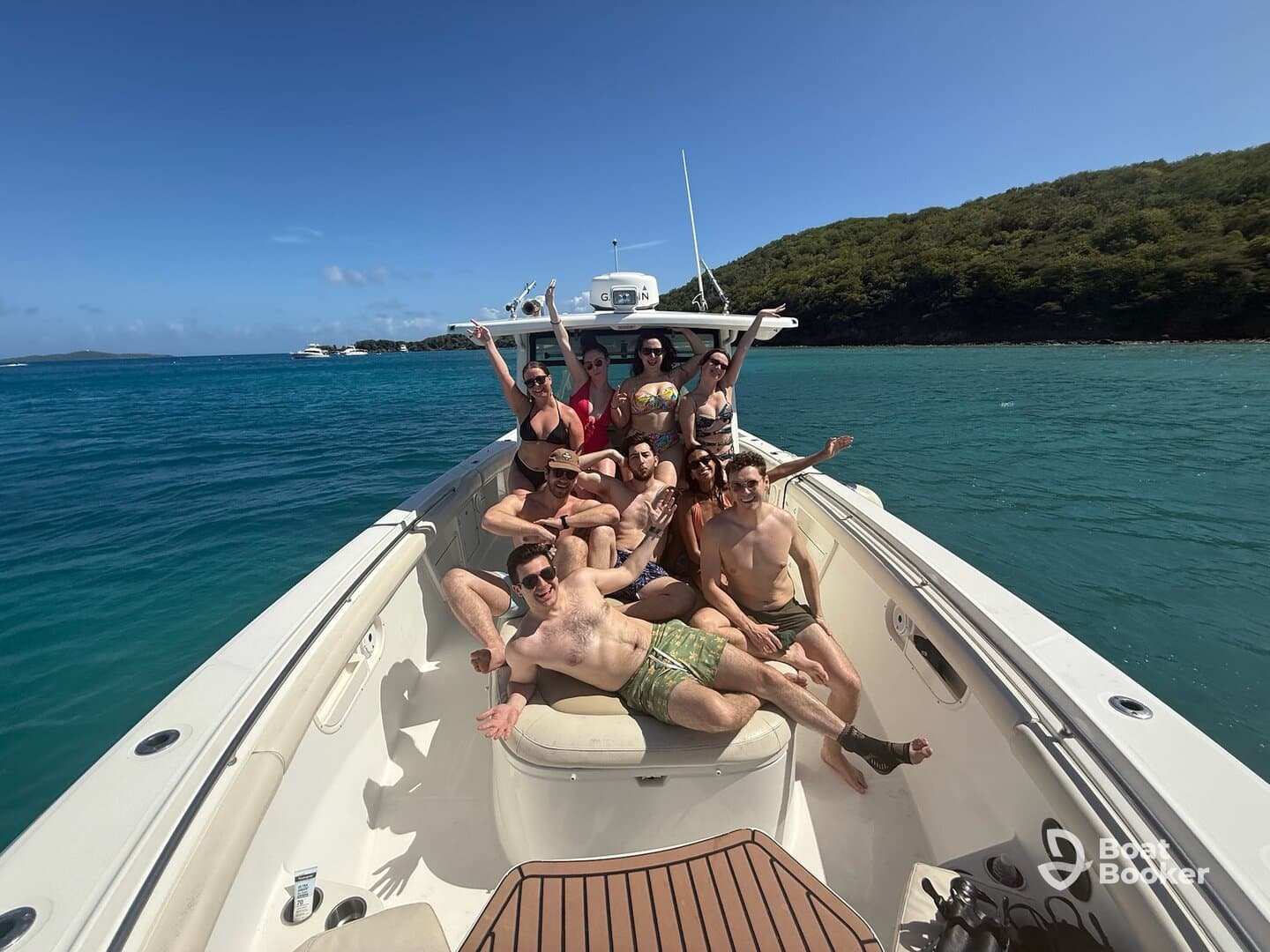 A lively group enjoys a fun day on the boat, soaking up the sun and celebrating together in beautiful turquoise waters.