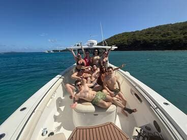 A lively group enjoys a fun day on the boat, soaking up the sun and celebrating together in beautiful turquoise waters.
