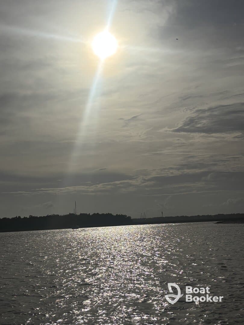 A scenic view of the sun reflecting on the water, creating a serene atmosphere, but the image lacks clarity and detail.