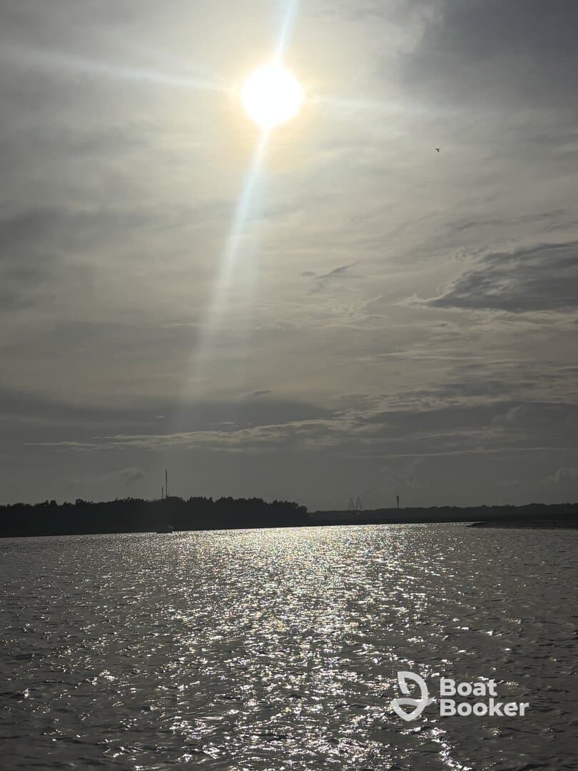 A scenic view of the sun shining over water, creating a shimmering effect, but the image lacks clarity and focus.