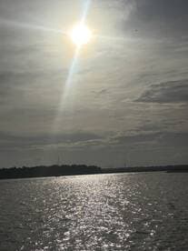 A scenic view of the sun reflecting on the water, creating a serene atmosphere, but the image lacks clarity and detail.