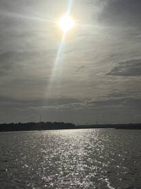 A scenic view of the sun shining over water, creating a shimmering effect, but the image lacks clarity and focus.