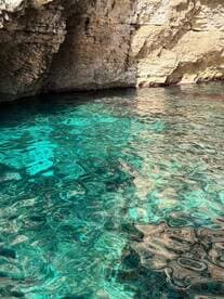 An unclear view of turquoise waters and rocky cliffs, creating a serene coastal atmosphere.