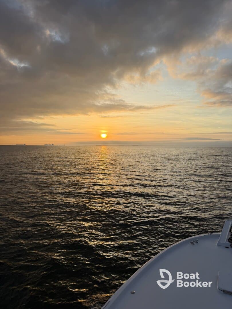 A serene sunset view over the water with the bow of a boat in the foreground, creating a picturesque scene perfect for evening cruises.